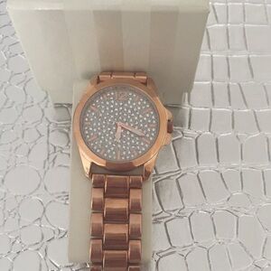 Rose gold watch with crystal encrusted face.